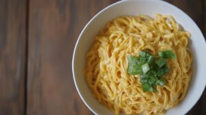 A bowl of freshly cooked noodles topped with chopped green onions, ready for Khao Soi preparation